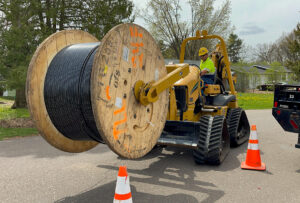 Fiber construction team moving spool of fiber optic cable